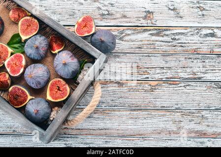 Figues dans une boîte en bois sur un fond blanc en bois. Espace libre pour le texte. Vue de dessus. Banque D'Images