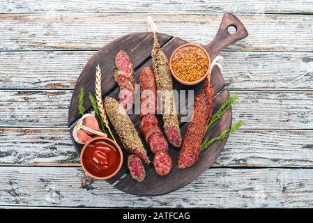 Fuete saucisse, salami, patroni sur le tableau noir de la cuisine. Sur un fond en bois blanc. Vue de dessus. Espace libre pour votre texte. Banque D'Images