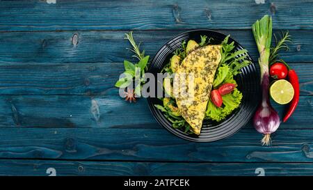 Omelette avec légumes et avocats. Œufs frits. Sur un fond en bois. Vue de dessus. Espace de copie disponible. Banque D'Images