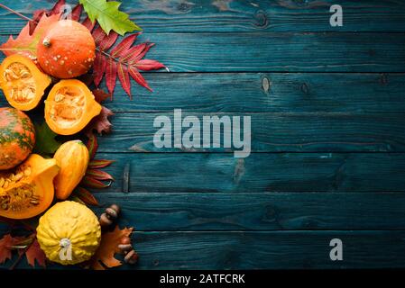 Légumes d'automne. Citrouilles colorées avec feuilles d'automne. Plat. Sur fond bleu en bois. Vue de dessus. Espace libre pour votre texte. Banque D'Images