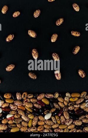 Différents haricots dispersés sur la table. Produits naturels sur fond sombre. Banque D'Images