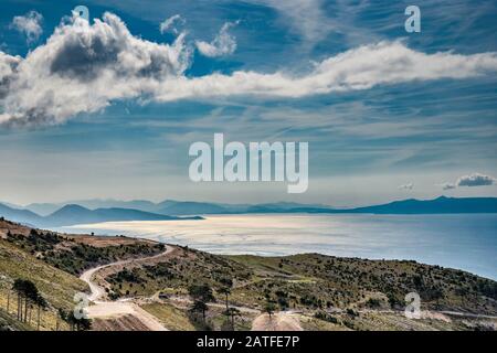 Vue rétroéclairé sur la mer Ionienne, île grecque de Corfou à distance, du point de vue près du col de Logara (Logarase, Logaraja), Riviera albanaise, Albanie Banque D'Images