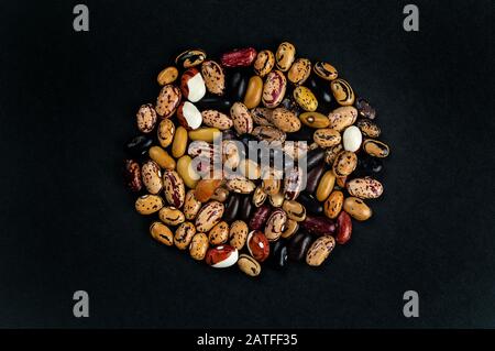 Différents haricots dispersés sur la table. Produits naturels sur fond sombre. Banque D'Images