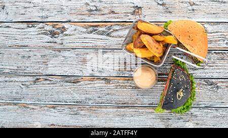 Pommes de terre cuites au four et hamburgers avec viande, tomates et oignons. Sur un fond en bois. Espace libre pour le texte. Vue de dessus. Banque D'Images