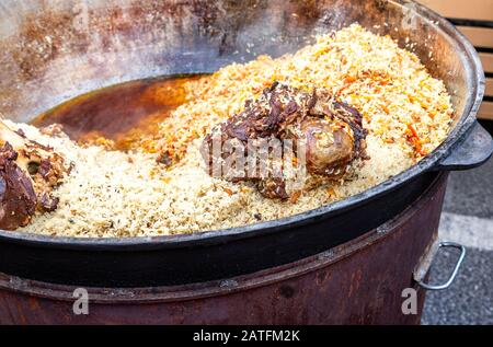 Appétissant pilaf ouzbek traditionnel dans un grand chaudron. Cuisine de rue. Cuisine extérieure Banque D'Images