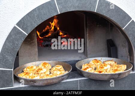 Four avec bois de chauffage brûlant et langues vives de flammes chauffées pour la cuisson des tartes et autres produits savoureux. Cuisine extérieure Banque D'Images