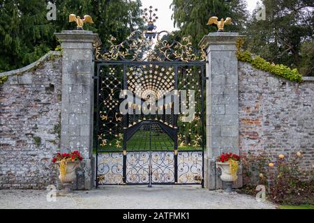 Ornement forgé grande porte de jardin en fer au mur de pierre. Or et noir Banque D'Images