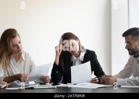 Les gens d'affaires contrariés s'assoient à la réception et ne sont pas satisfaits de lire le rapport financier Banque D'Images