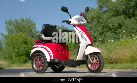 Vue à angle bas du scooter électrique sur la route. E-véhicule élégant rouge. Transport respectueux de l'environnement, véhicule de transport alternatif Banque D'Images