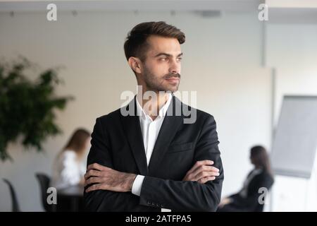 Homme d'affaires millénaires confiant en toute confiance en costume formel se posant à l'intérieur Banque D'Images