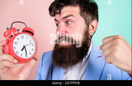 Le temps de travail. L'homme d'affaires agressif barbu tenir réveil. Le concept de stress. Horaire de travail stressantes hipster. Businessman a faute de temps. La gestion du temps. Combien de temps jusqu'à ce délai. Banque D'Images