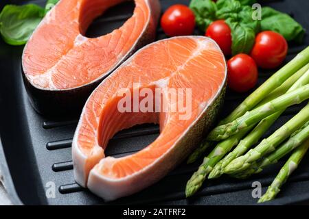 Biftecks et légumes de saumon crus non cuits dans la vue rapprochée de la poêle à gril. Des aliments sains Banque D'Images