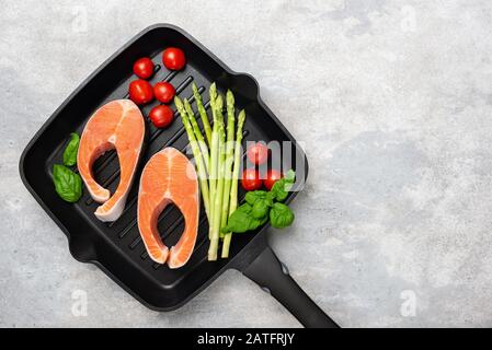 Steaks et légumes de saumon non cuits sur la poêle à gril. Cuisine dîner sain. Vue de dessus avec espace de copie pour le texte ou la conception Banque D'Images