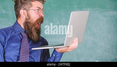 Informations choquantes. Hipster professeur porter lunettes et cravate tient ordinateur portable surfer sur Internet. Des nouvelles choquantes. Professeur barbu choqué l'homme avec un ordinateur portable moderne surfer sur Internet tableau de surveillance arrière-plan. Banque D'Images