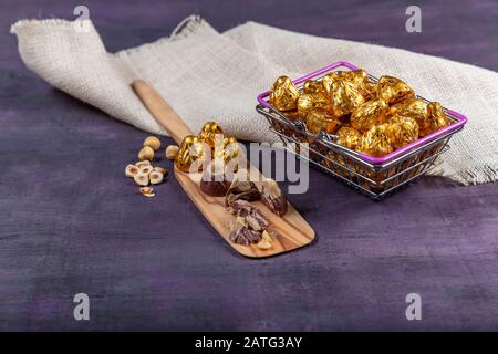 Une boîte de chocolats en feuille d'or. Grande boîte de bonbons au chocolat en feuilles d'or sur fond de bois violet. EID al-Fitr (Fête du Ramadan) conce Banque D'Images