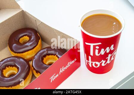 Une boîte de beignets au chocolat Tim Hortons avec une tasse de café Banque D'Images