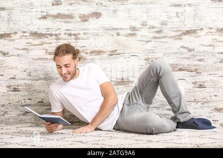 Beau livre de lecture de l'homme près de mur en bois Banque D'Images