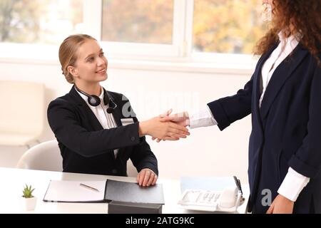 La femme secrétaire se secoue les mains avec le visiteur au bureau Banque D'Images