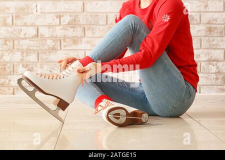 Jeune femme qui nouait des lacets sur des chaussures de skate à l'intérieur Banque D'Images