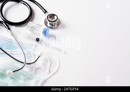 Stéthoscope avec masque de protection par injection ou masque médical allongé sur fond blanc. Protéger Le Coronavirus. Banque D'Images