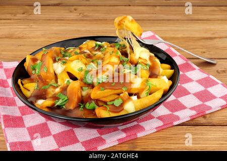 Bol de poutine canadienne traditionnelle sur fond de bois Banque D'Images