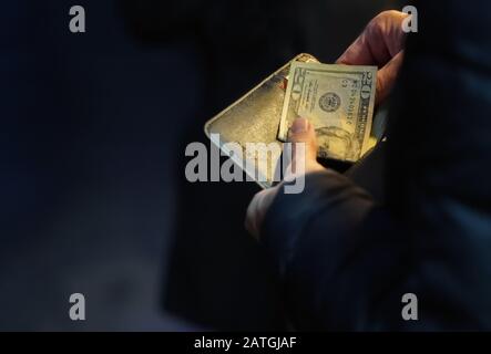 New York, NY / USA - 29 décembre 2019: Gros plan des mains prenant une facture de vingt dollars d'un portefeuille en cuir noir Banque D'Images