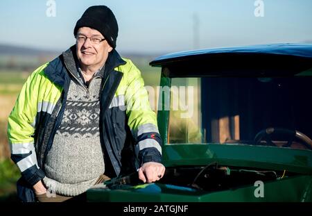 Bockenem, Allemagne. 21 janvier 2020. Horst-Dieter Görg, membre du conseil d'administration du groupe d'intérêt Hanomag, se trouve à côté de la ville et de la voiture de service électriques de 1922 'HAWA EM 3' la voiture électrique, propriété du fournisseur d'électricité BS Energy, est restaurée dans l'atelier du groupe d'intérêt Hanomag à Bockenem-Störy. Crédit: Hauke-Christian Dittrich/Dpa/Alay Live News Banque D'Images