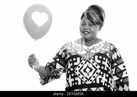 Heureuse femme africaine en surpoids tenant ballon avec signe de coeur prêt pour la Saint-Valentin Banque D'Images