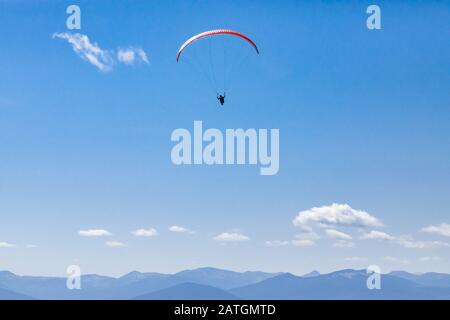 Belle scène de parapente en vol au-dessus des montagnes de la vallée de Kootenay. Tir long de l'homme de parapente en vol. Sports d'aventure récréatifs et compétitifs Banque D'Images