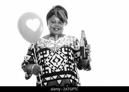 Heureuse femme africaine en surpoids tenant ballon avec signe de coeur et bouteille de bière Banque D'Images