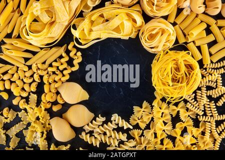 Modèle de pâtes italiennes avec un endroit pour le texte, une couche plate d'une variété de types de pâtes, tiré du dessus sur un fond noir Banque D'Images