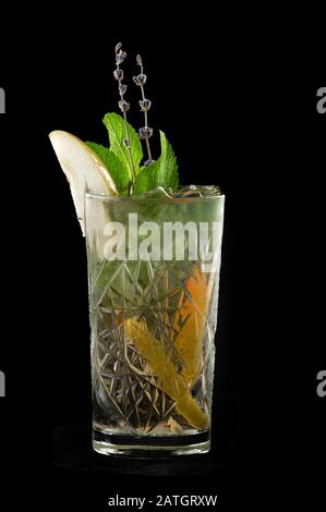 Un cocktail frais et frais de poire, de citron et de menthe. Le cocktail est décoré avec une branche de lavande. Isolé sur un fond noir. Banque D'Images