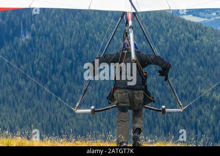 Vue arrière de l'homme de planeur professionnel Hang courir et prendre. Deltaplane en action - vol depuis le sommet de la montagne Banque D'Images