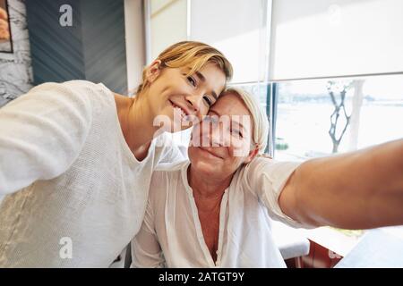 Une femme mûre positive prenant selfie avec sa fille adulte la rendant à la maison Banque D'Images
