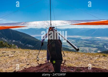 Homme avec un deltaplane pour descendre du sol au sommet de la montagne. Parapente prêt pour un vol. Un pilote de plan Delta sur le point de se lancer Banque D'Images