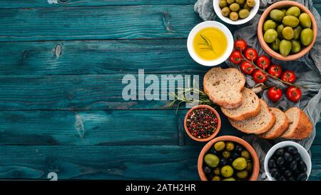 Un ensemble d'olives vertes et d'olives noires, ainsi que des collations. Sur une table en bois bleu. Espace libre pour le texte. Banque D'Images