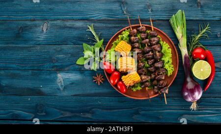 Brochettes de coeurs de poulet, maïs et légumes frais. Sur un fond en bois. Vue de dessus. Espace de copie disponible. Banque D'Images