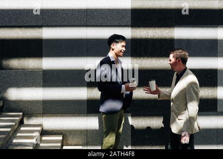 Les dirigeants d'entreprise en riant positivement buvant du café et en parlant des dernières nouvelles et en plaisantant autour Banque D'Images
