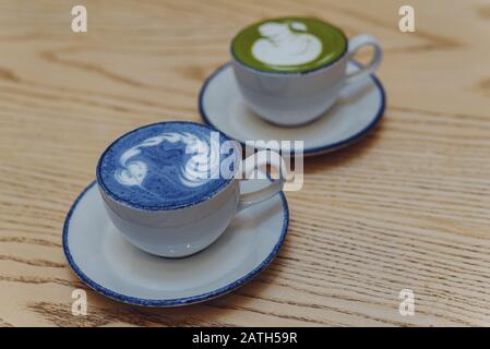 Matcha bleu et vert dans des mugs blancs en céramique sur une table en bois avec copyspace. Banque D'Images