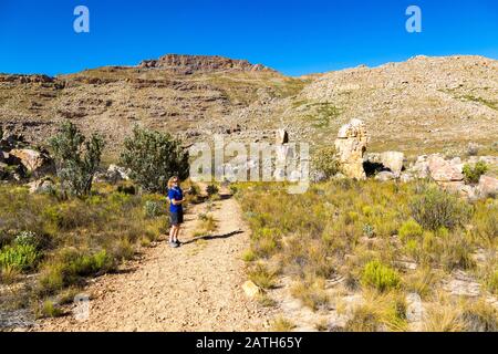Vue sur le sentier de randonnée de la Croix maltaise - une destination de randonnée populaire dans la région de Cederberg (Afrique du Sud) avec une jeune femme pointant vers le mont Banque D'Images