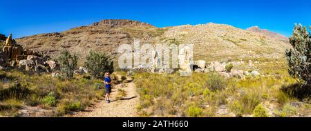 Vue panoramique sur le sentier de randonnée de la Croix maltaise - une destination de randonnée populaire dans la région de Cederberg (Afrique du Sud) avec une jeune femme pointant vers Banque D'Images