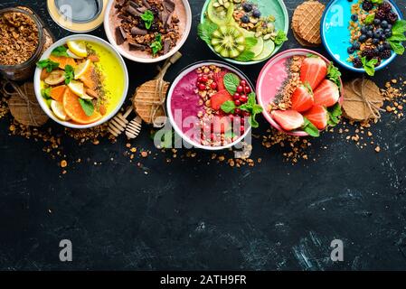 Un excellent ensemble de smoothies aux fruits colorés avec yaourt, fruits frais et baies. Un petit déjeuner sain. Vue de dessus. Espace libre pour votre texte. Sur un dos noir Banque D'Images