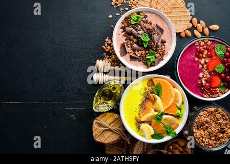 Un excellent ensemble de smoothies aux fruits colorés avec yaourt, fruits frais et baies. Un petit déjeuner sain. Vue de dessus. Espace libre pour votre texte. Sur un dos noir Banque D'Images