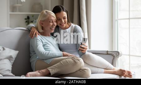 Une maman heureuse d'âge moyen et une fille grognée font du selfie sur smartphone Banque D'Images
