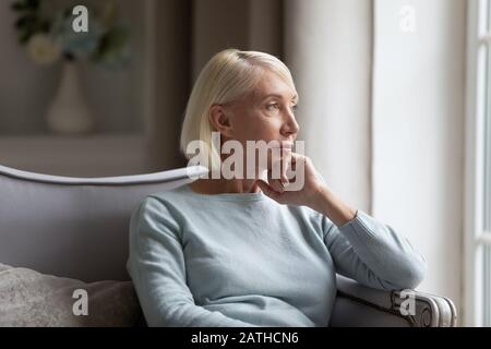 Une femme pensive d'âge moyen regarde dans la pensée à distance Banque D'Images