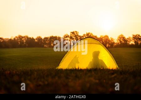 Camping et voyage dans la nature, tente avec les silhouettes d'une femme et de son chien Banque D'Images