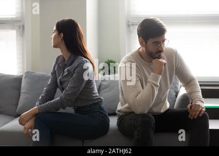 Jeune couple assis sur le canapé séparément l'un de l'autre Banque D'Images