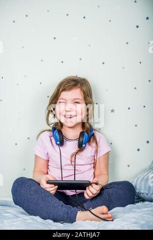 Concept de jeux vidéo pour les enfants. Très petite ou jeune fille, jouer avec joystick, smartphone, lunettes VR et casque, profiter de jeux, assis Banque D'Images