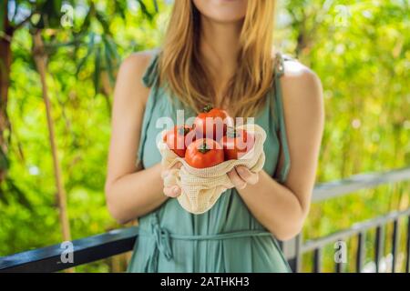 Tomates dans un sac réutilisable entre les mains d'une jeune femme. Concept zéro déchet Banque D'Images