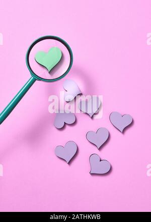 Motif de vacances avec petits coeurs et grande loupe au-dessus d'un coeur vert sur un fond rose pastel, espace de copie. Voiture de Saint Valentin Banque D'Images